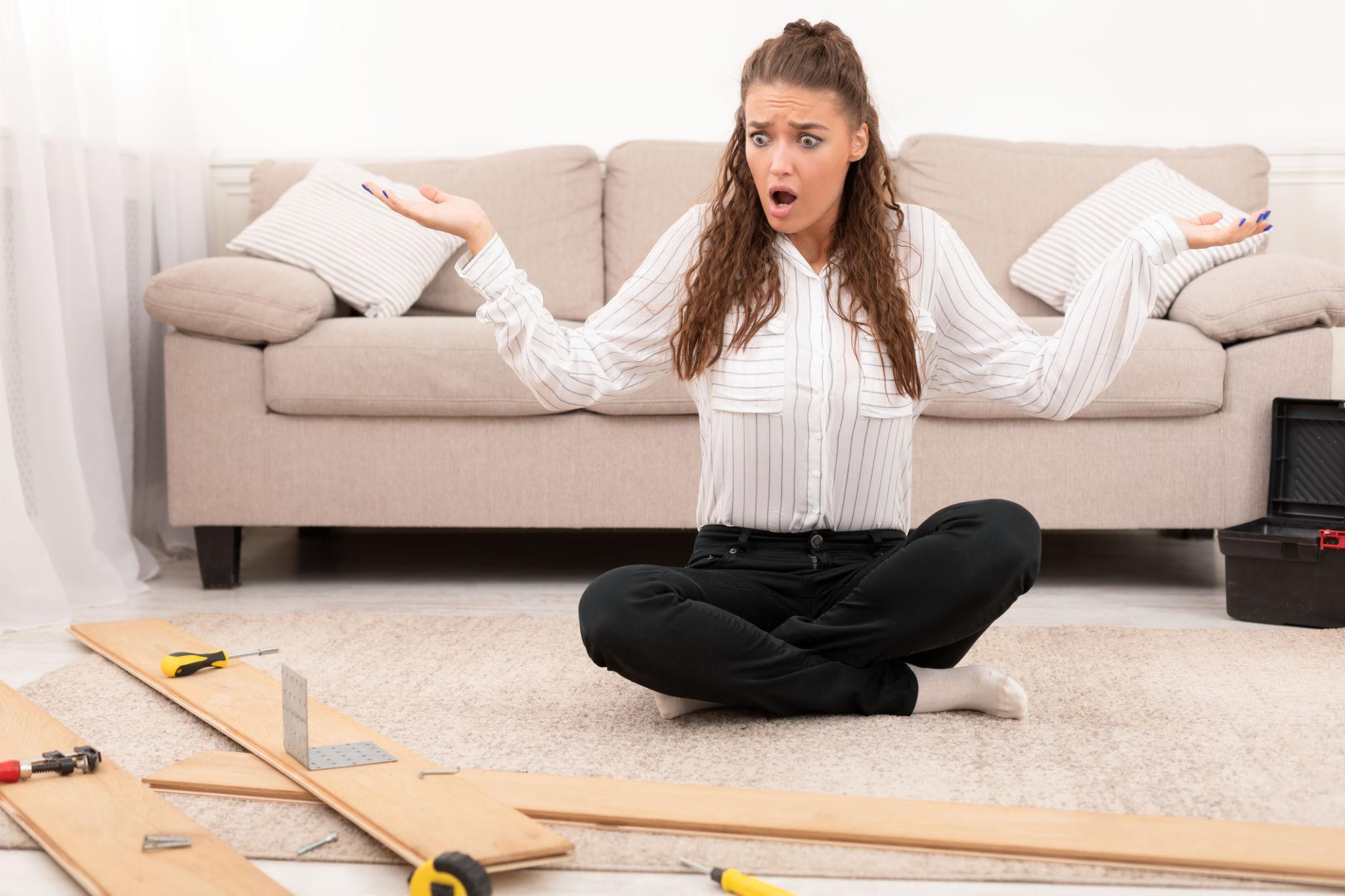 Person confused trying to assemble IKEA furniture on the floor